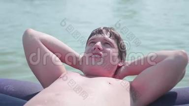 一个年轻人在充气床垫上游泳。 积极的情绪。 夏日炎炎